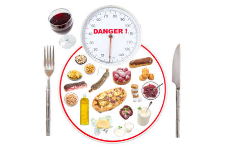 Diet healthy eating weight scale concept : plate representing weight scale focus on scale dial with various unhealthy food on white backgroundの写真素材