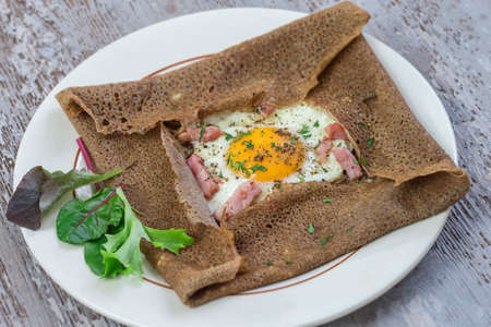 french Buckwheat crepe galette with bacon and egg for tasty healthy lunch on grey wooden backgroundの写真素材