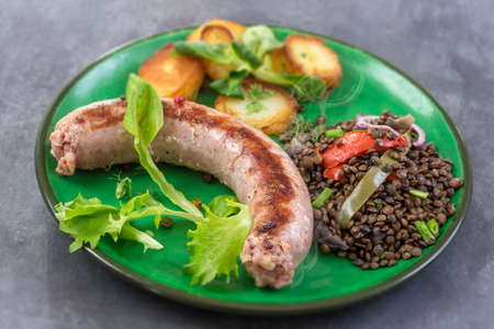 France Grilled Toulouse sausage with roasted potatoaes and salad and lentils on old wooden backgroundの写真素材