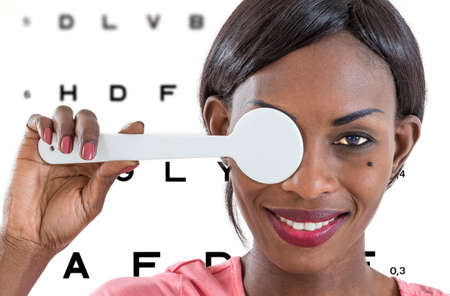 Young African lady taking an eyesight test examination at an optician clinic whith Eye Chart...