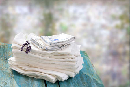 stack of white and blue linen napkins on a wooden table with a blury wall backgroundの写真素材