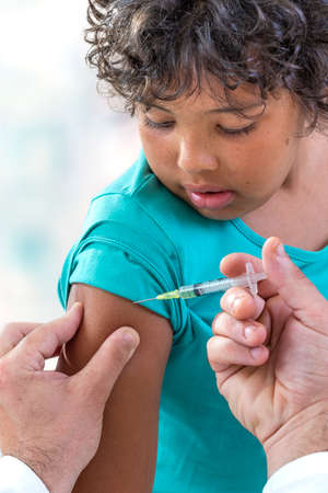 Vaccination. Young boy receiving vaccination immunisation by professional health worker, focus on shoulderの写真素材