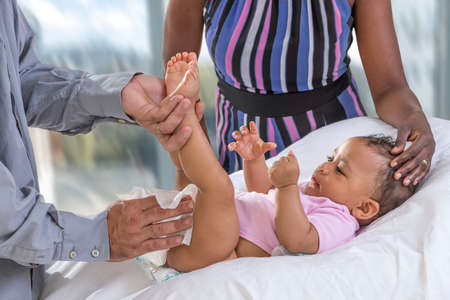 Baby Changing. Loving father changing diaper of his baby daughter.,Little child, girl on changing table while mum is looking cheerfulyの写真素材