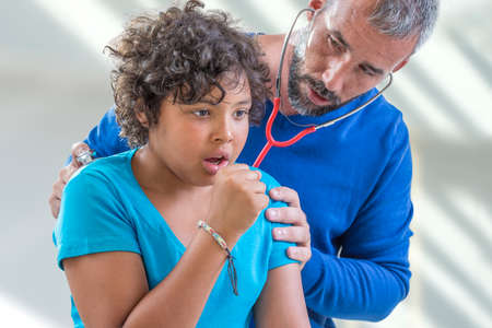 young boy flu. doctor examines a young teen boy colds listen to the lungs with a stethoscope while...