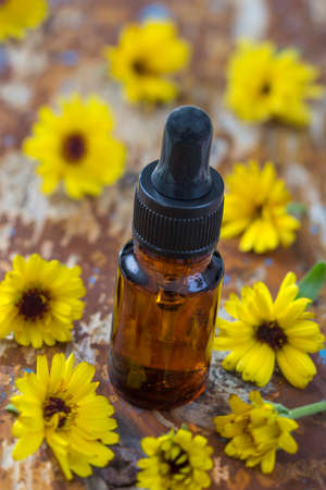 Essential aroma oil with calendula flowers on wooden background. .の写真素材