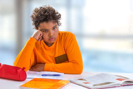 Tired shoolboy. teenager boy frustrated by doing homework indoors unwilling to work