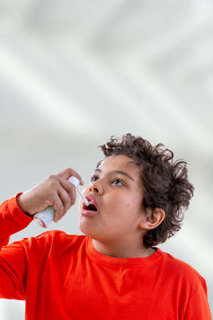 Boy splashes in his mouth with a spray from the pain in her throat.