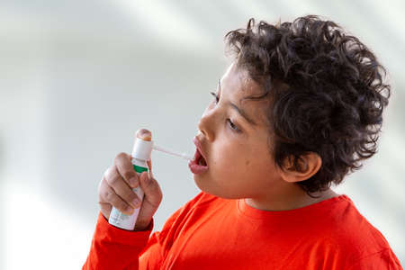 Boy splashes in his mouth with a spray from the pain in her throat.の写真素材