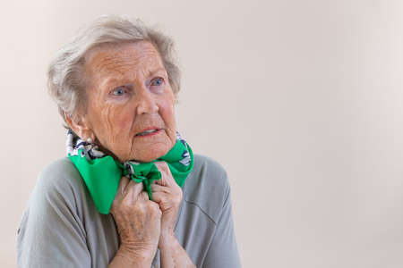 senior woman l has bad cough, uses tissue, wears scarf on neck, feels unwell and unhealthy, .の写真素材
