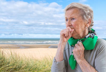 senior woman l has bad cough, uses tissue, wears scarf on neck, feels unwell and unhealthy seaside...