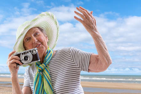 Senior woman at the beach with old vintage camera the sea on backgroundの写真素材
