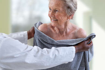 Care giver or nurse assisting elderly woman for showerand drying herの写真素材