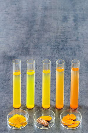 Test tube with mater and curcuma with turmeric powder and turmeric root on slate backgroundの写真素材
