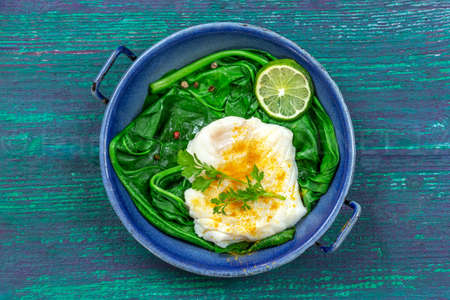 Cod fillet with rice and spinach garnish with curry, in vintage pan on wooden backgroundの写真素材