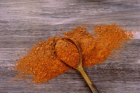 Dry Red clay mask for face and body in a wooden spoon. Isolated on old wooden background