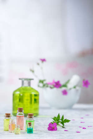 Essential geranium oil in bottle and geranium flowers,Meadow geranium essential oilの写真素材