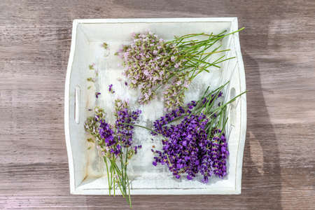 wooden tray with beautiful pink and purple lavender flowers on wooden tableの写真素材