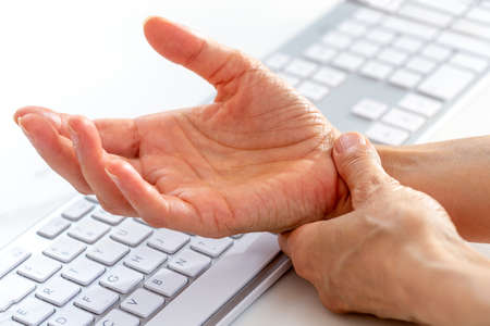 Office syndrome concept. Closeup woman holding her wrist pain from using computer long time.の写真素材