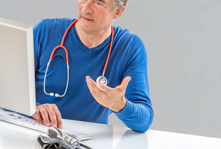 Online medical consultation: Doctor expplaining diagnosis while sitting in hfront computer with patientの写真素材