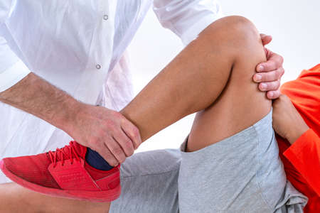Doctor examining boy leg because of knee problem symptomset hospitalの写真素材