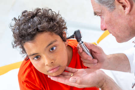 Ear examination. Paediatrician using an otoscope to examine a young boys ear. the hospitalの写真素材