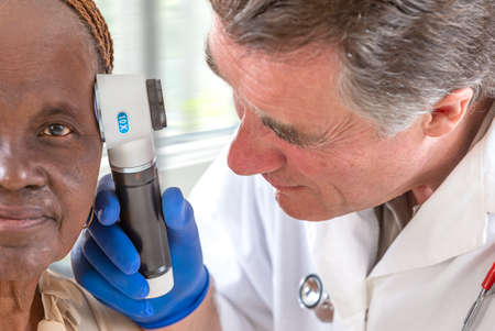 Elderly woman getting check-up at dermatologist.,usig magnifying glass