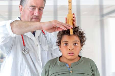 A doctor measures the height of a boy teenager during medical consultation -12-14-years