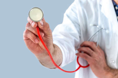 Close-up of a male doctor s hand holding a stethoscope outstretched towards the viewer. Healthy lifestyle concept. Copy space.の写真素材