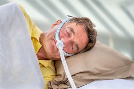 Man wearinhg a maslk Sleep Apnea and CPAP. Prescription, to sleep for safe lifeの写真素材