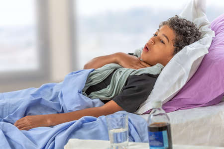 Little girl is sick. Mercy, malaise.at home touching sore throatの写真素材