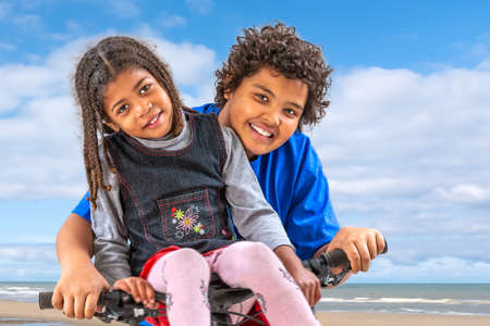 6 years old girl on on the handlebars and 10 years old brother riding a bicycleの写真素材