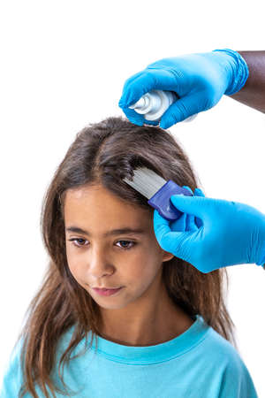 Mother treating daughters hair against lice with spray treatmentの写真素材