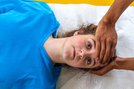 Close up of physiotherapist manipulating body part on young woman. Girl laying on madical bedの写真素材