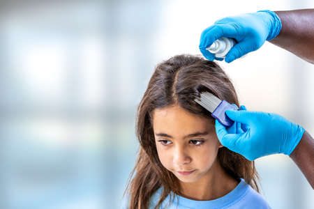 Mother treating daughters hair against lice with spray treatmentの写真素材