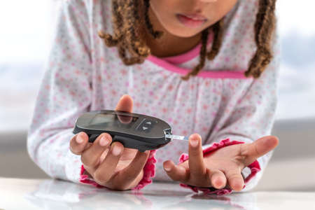 Concept children diabetes children with glucometer learning to check blood sugar level at home. Learn to use a glucometerの写真素材