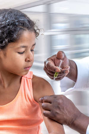 Little suspicious girl get an injection, vaccination at hospitalの写真素材