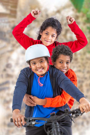 6 and 12 years old girl and boys riding a bicycle. in the gardenの写真素材