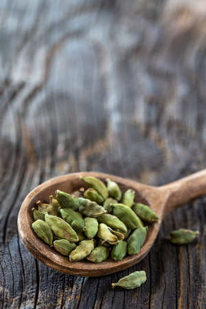 Cardamom in wooden spoon isolated on wodenの写真素材
