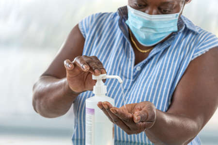 Business woman working from home wearing protective mask. Business woman in quarantine for wearing protective mask. Working from home. Cleaning her hands with sanitizer gel.の写真素材