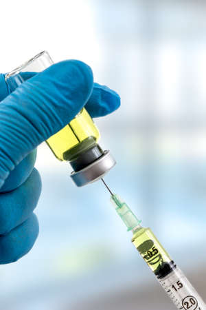 Gloved hands holding a syringe while loading a dose. Concepts of medical treatment, epidemic or vaccineの写真素材