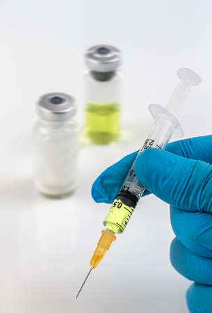 Gloved hands holding a syringe while loading a dose. Concepts of medical treatment, epidemic or vaccineの写真素材