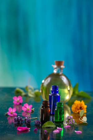 Bottles of essential oil, mortar and pestle with lavender flowers on light blueの写真素材