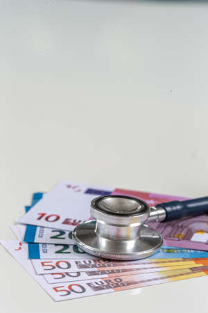 a stethoscope on a wad of euro bills, depicting the concept of the health care costsの写真素材