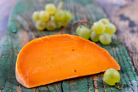 Piece of tasty mimolette cheese isolated on wooden backgroundの写真素材