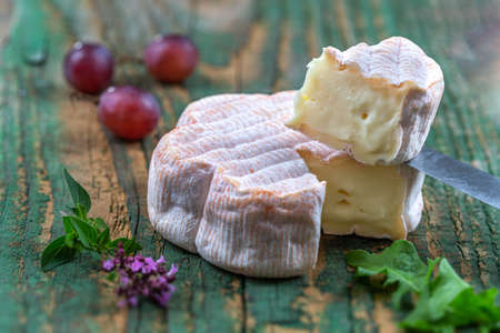 French Saint Albray cheese, slices on wooden cutting board, rustic style with grapes