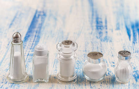 Various Salt shaker isolated on white and white wooden background