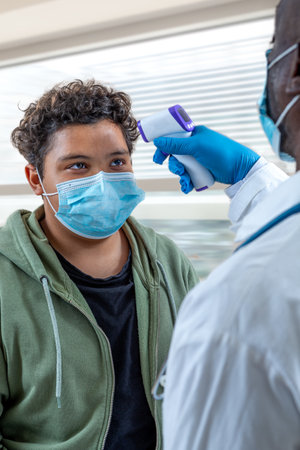 Coronavirus. Nurse or doctor checks boys body temperature using infrared forehead thermometer gun - epidemic outbreak concept. .の写真素材