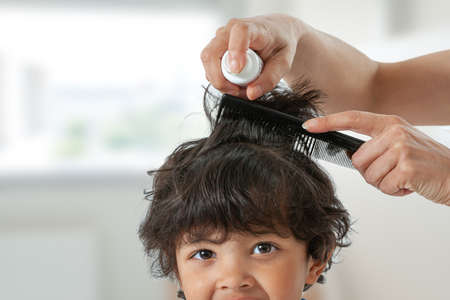 Mother treating daughters hair against lice. Head lice treatment for schoolchild.の写真素材