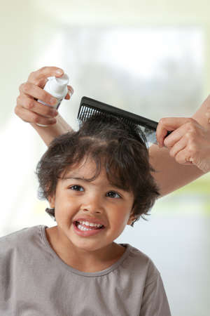 Mother treating daughters hair against lice. Head lice treatment for schoolchild.の写真素材