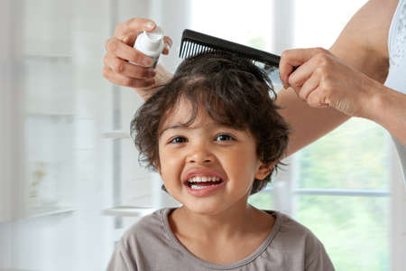 Mother treating daughters hair against lice. Head lice treatment for schoolchild.の写真素材
